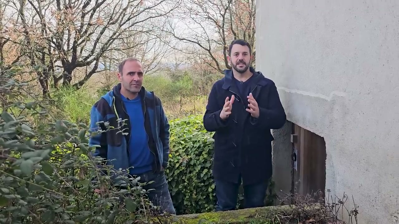 Les explications se poursuivent devant une paroi de la maison.