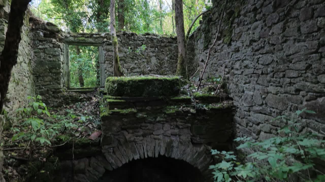 Vestiges en pierre de l’ancien moulin avec une meule au-dessus d’une ouverture voûtée